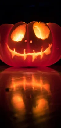 Looking for a spooky Halloween live wallpaper? Look no further than this chilling image of a lit up pumpkin sitting on a table