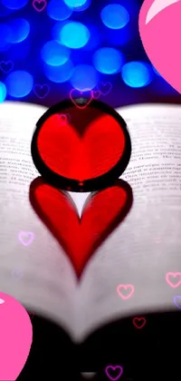 This mobile live wallpaper features a heart-shaped ring atop an open book, with a picture in the background