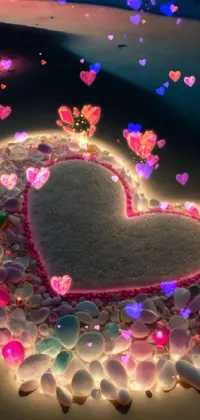 This live wallpaper depicts a heart made of stones on the beach, with glowing accents that evokes a sense of peace and quiet