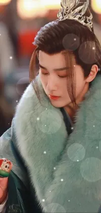 This stunning live wallpaper features a regal woman donning a crown atop her head in sky-blue thick fur over a green robe, accompanied by a handsome and stylish male