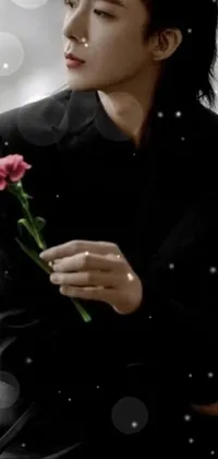 This phone live wallpaper depicts a stunning close-up of a hand holding a flower set against a colorized background
