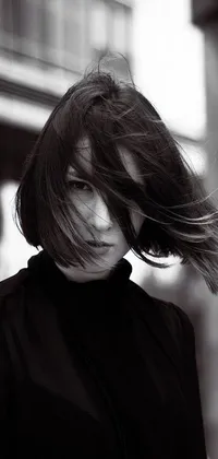 This black and white phone live wallpaper features a captivating photo of an androgynous person with short black bob hair blowing in the wind