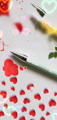This romantic phone live wallpaper features two pens on a paper, with falling hearts to add playfulness