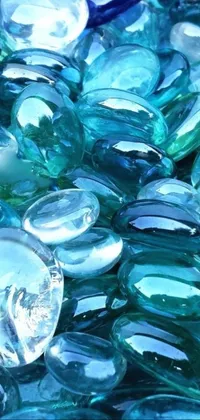 This stunning phone live wallpaper features a pile of smooth blue and green glass pebbles, arranged in a beautiful pile that creates a mesmerizing and calming effect on your phone screen