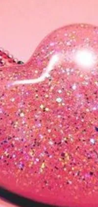 This vibrant live wallpaper features a heart-shaped object on a pink surface embellished with glitter, shiny jewels, and glam fashion accessories