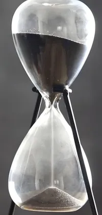 This phone live wallpaper features a breathtaking image of an hourglass sitting on a wooden table