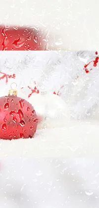 This phone live wallpaper features a red and white Christmas ornament set against a snowy backdrop