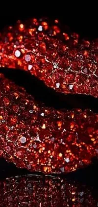 This live wallpaper displays a close-up of a red glittered lipstick coated in precious stones, resting on a sleek black surface