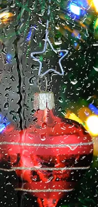 Enjoy a beautiful live wallpaper on your phone with a red ornament sitting on top of a rain-covered window