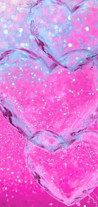This pink phone live wallpaper features a digital painting of three hearts, covered in water droplets and sparkling colors
