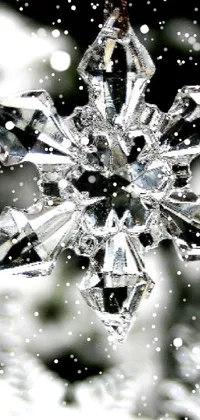 This stunning phone live wallpaper features a close-up of a snowflake hanging from a tree