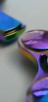 This Live Wallpaper features a colorful macro photograph of a kinetic art fidgetr on a table