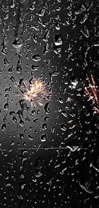 This live phone wallpaper features a mesmerizing firework exploding in the center of a rain-covered window