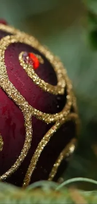 This phone live wallpaper captures the essence of the holiday season with a close-up shot of a mesmerizing red and gold Christmas ornament