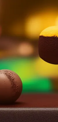 This phone live wallpaper showcases a delectable chocolate ball and succulent orange sitting on a table