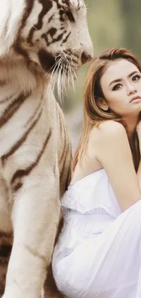 This phone live wallpaper features a stunning woman sitting beside a white tiger against a lush jungle backdrop