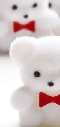 This phone live wallpaper showcases a group of adorable white teddy bears donning red bow ties set against a vibrant iPhone background