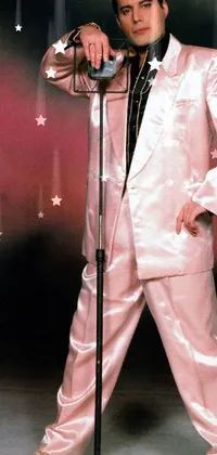 This phone live wallpaper features a charismatic man in a eye-catching pink suit and white silky outfit holding a microphone on stage