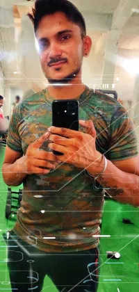 Transform your phone screen into a futuristic battleground with this live wallpaper! Featuring an army-inspired outfit, this muscular man is holding a gun while taking a selfie in a mirror