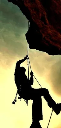 This phone live wallpaper features a stunning silhouette of a person rock climbing against a scenic backdrop of the great outdoors