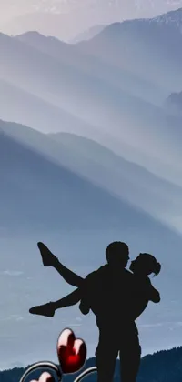 Looking for a mesmerizing wallpaper for your phone that exudes romance and dreaminess? Look no further than this stunning live wallpaper featuring a black and white silhouette of a man carrying a woman on his back amidst a backdrop of majestic mountains, twinkling stars, and a radiant moon