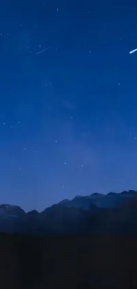 This phone live wallpaper showcases a stunning shooting star in the night sky with mountains in the background