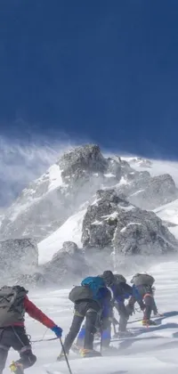 This phone live wallpaper features a group of skiers conquering a snowy slope, with dusty rocks in the background creating a thrilling atmosphere