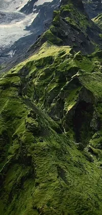 This phone live wallpaper features a mountain covered in green grass beside a glacier, in hyperdetailed ultra-high definition