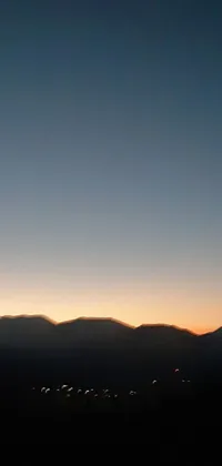 This phone live wallpaper depicts a stunning sunset over distant mountains, against a clear night sky