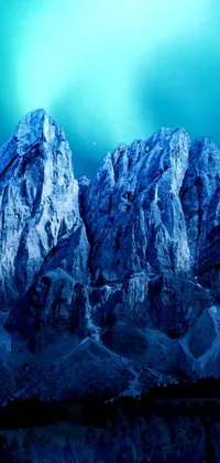 This phone live wallpaper features a breathtaking digital matte painting of a snow-covered mountain towering above a dense forest, with beautiful blue lights adding a magical feel