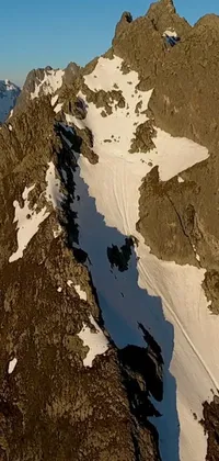 This live phone wallpaper features an incredible aerial view of a snowy mountain, with panoramic footage cut into the side of the stark landscape