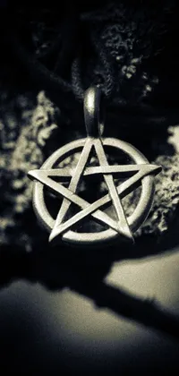 Looking for a striking live wallpaper that exudes gothic vibes? Our black and white photo of a pentagram amulet by Niko Henrichon is the perfect fit