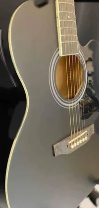 Are you a music fanatic? Our phone live wallpaper features a close-up of a guitar on a stand with black and grey shades and gold accents
