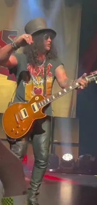 This phone live wallpaper depicts a rugged, rock-and-roll man standing confidently on a stage holding a Gibson Les Paul guitar