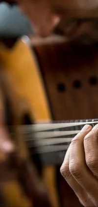 This dynamic phone wallpaper depicts a striking image of a musician strumming a guitar at close range