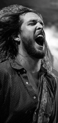 Bring your phone wallpaper to life with this captivating live wallpaper! Featuring a black and white photo of a man with long hair, rocking out on his guitar while screaming into the air, this wallpaper is truly a work of art