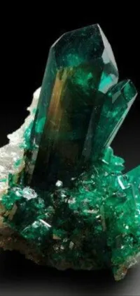 This beautiful phone live wallpaper features a detailed image of a green crystal situated on a rocky surface