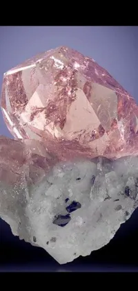 This phone live wallpaper showcases a stunning pink diamond sitting atop a rocky surface with surrounding crystals