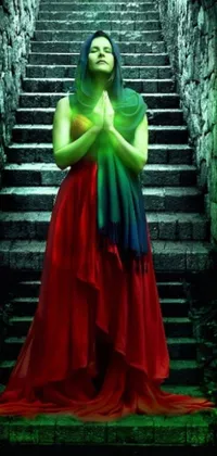 This phone live wallpaper showcases a gorgeous woman draped in a flowing red dress, standing elegantly on a set of stairs enveloped in lush greenery