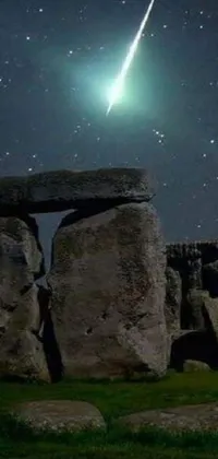 This animated wallpaper features a shooting star above the iconic Stonehenge monument, with glowing green crystals scattered throughout the scene