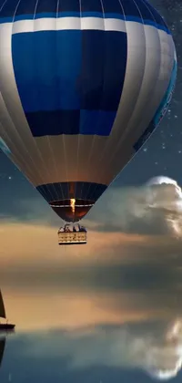 This stunning live wallpaper features a blue and white hot air balloon sailing over a serene, dream-like body of water