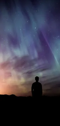 This phone live wallpaper boasts an awe-inspiring image of a man standing in front of a vibrant and colorful sky, brimming with light and space