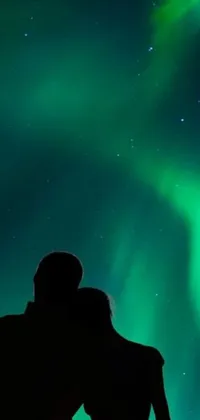 This live wallpaper captures a romantic scene of a man and woman observing the mesmerizing Northern Lights