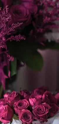 This phone live wallpaper showcases a gorgeous vase filled with delicate pink roses on a table, featuring dark purple hues and stunning high-definition footage