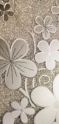 This unique live wallpaper features a stunning array of paper flowers elegantly arranged on a table, sitting atop a stylish art deco terrazzo pattern done in silver