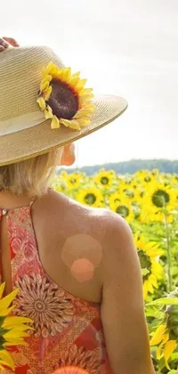 This phone live wallpaper depicts a beautiful blonde woman standing in a sunflower field wearing a wide sunhat
