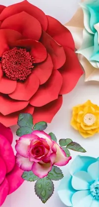 This live phone wallpaper showcases stunning paper flowers in red, teal, and yellow hues, with a giant rose taking center stage