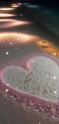 This stunning phone live wallpaper features a heart drawn on a sandy beach using chalk art