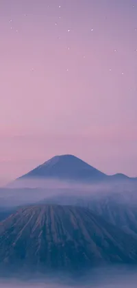 This phone live wallpaper depicts a majestic mountain range shrouded in mist, set against a stunning purple sky