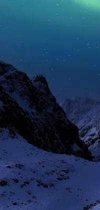 This phone live wallpaper showcases a group of individuals on top of a snow-covered mountain during the night under a magnificent moon-lit sky in the Himalayas